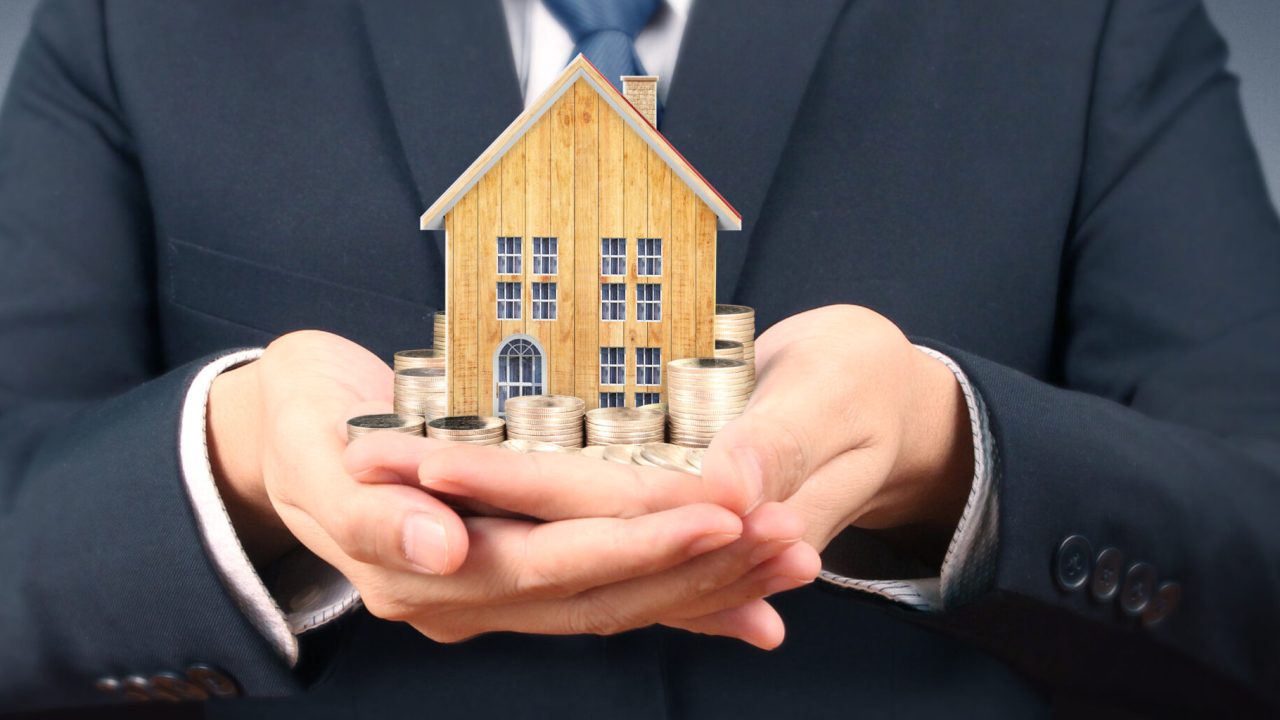 Growing coins house on stack coins in hand. Concept of Investment propert and finance investment concep